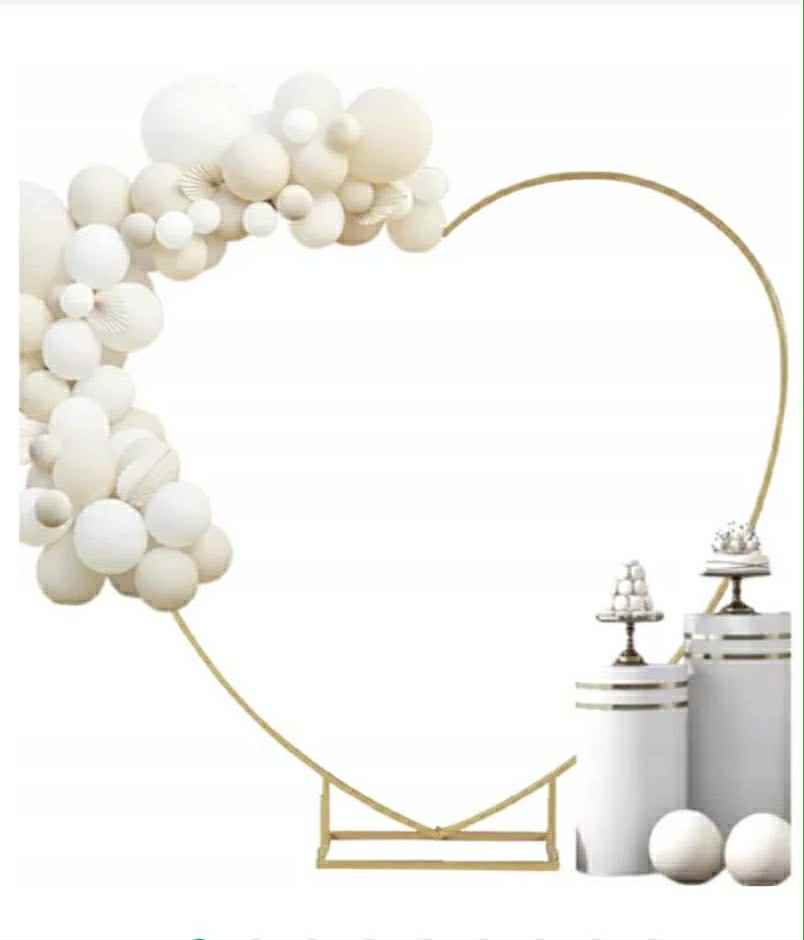 A decorative heart-shaped arrangement made of white balloons, accompanied by white cylindrical pedestals with decorative elements.
