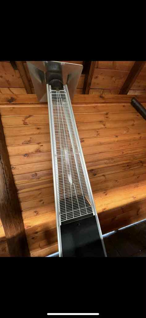 A ceiling-mounted heater with a metallic grid design, installed in a wooden interior space.